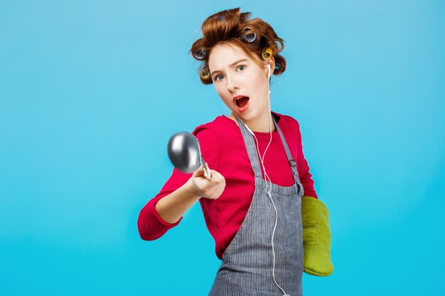 Lustiges Mädchen tanzt beim Kochen des Abendessens mit grünem Handschuh zur Hand