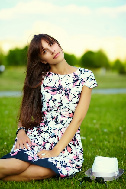 Lustiges stilvolles lächelndes schönes junges Frauenmodell im hellen Sommerkleid des Hutes im Hut im Park