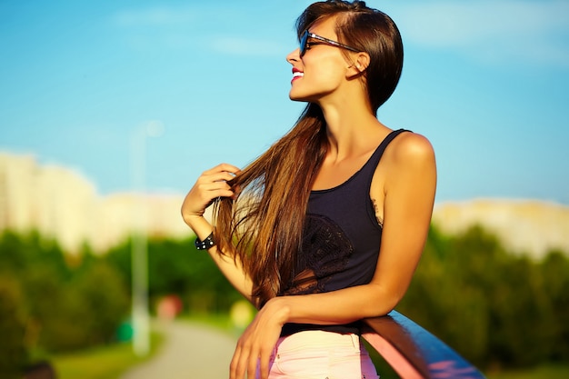 Lustiges stilvolles sexy lächelndes schönes schönes Sonnenbadmodell der jungen Frau im hellen Sommerhüfttuch des Sommers im Park