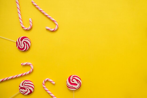 Lutscher und Zuckerstangen auf gelbem Hintergrund