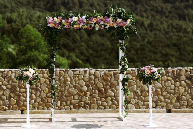 Luxus-Hochzeitsbogen mit üppigen Blättern, zarten Rosen und lila Hydrangea im Freien. Hochzeitsfloristik