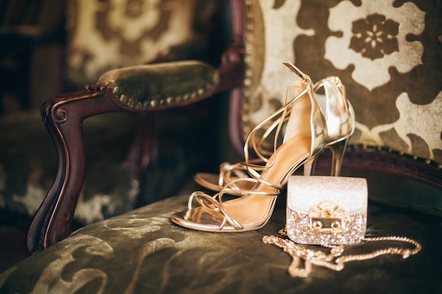 Luxusmode Damenaccessoires, goldene Stöckelschuhe, kleine Abendtasche, eleganter Stil, Vintage-Stil, Sandalenschuhe