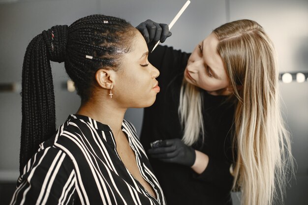 Mädchen Afrika. Frau, die Augenbrauen macht. Mädchen in einem Schönheitssalon.