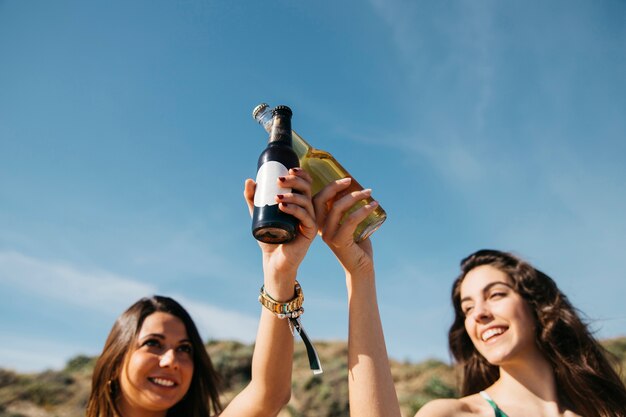 Mädchen am Strand, die mit Bier toasten