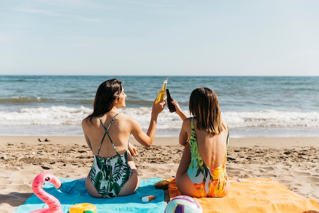 Mädchen am Strand toasten mit Bier