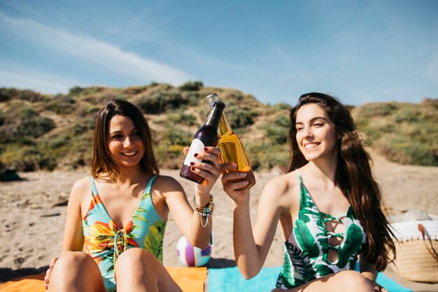 Mädchen am Strand toasten mit Bier