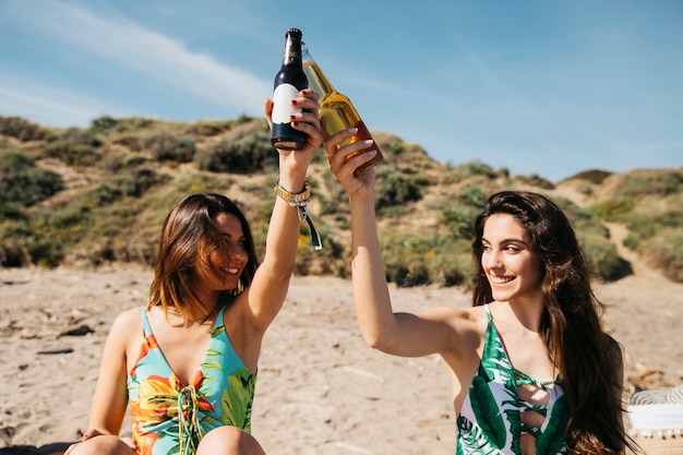 Mädchen am Strand toasten mit Bier