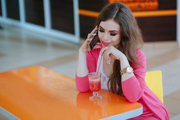 Mädchen an ihrem Soda, während auf dem Telefon sprechen