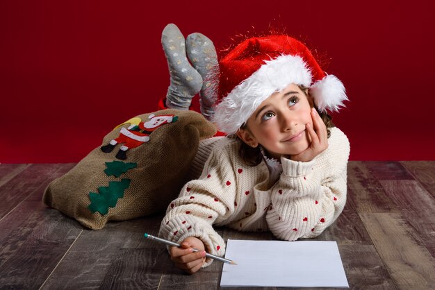 Mädchen auf dem Boden liegend nachdenklich mit einem Bleistift und einem Papier