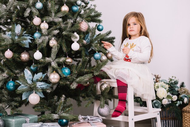 Mädchen auf dem Stuhl, der Weihnachtsbaum verziert