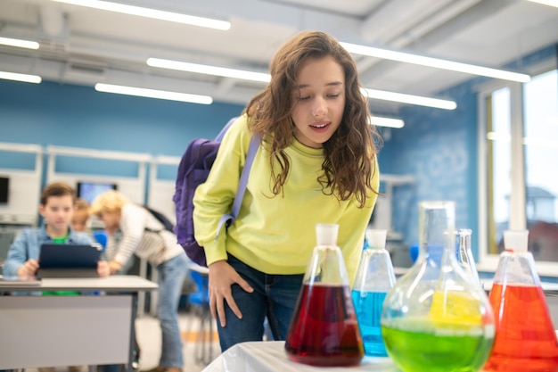 Mädchen beugt sich im Klassenzimmer über Laborflaschen