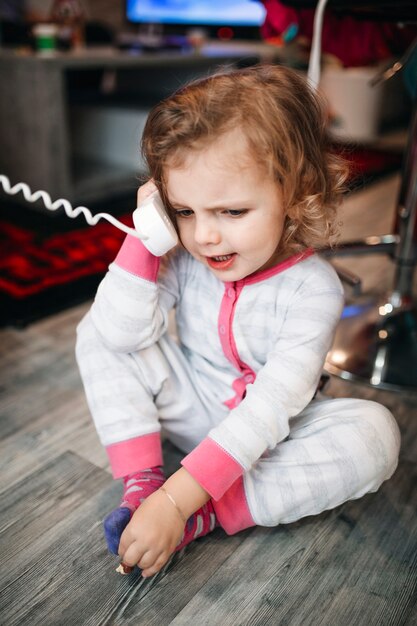 Kostenloses Foto mädchen, das am telefon auf fußboden spricht