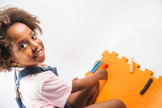 Mädchen, das auf Spielmatte mit Plasticine im Studio sitzt