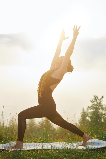 Mädchen, das auf Yogamatte in der Natur vorwärts tritt