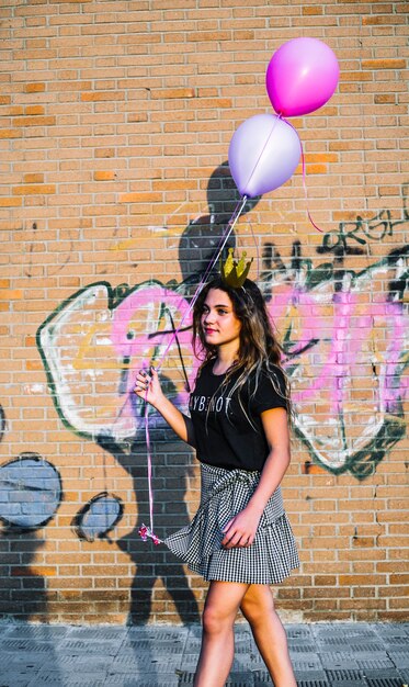 Mädchen, das Ballone vor Graffitiwand hält