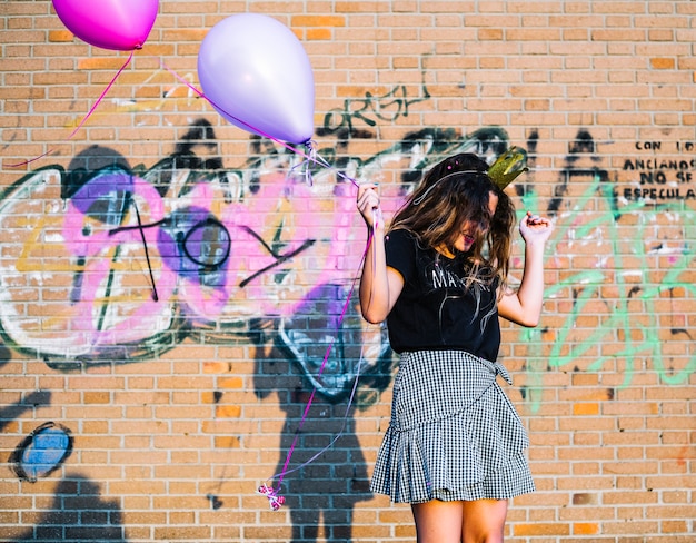 Kostenloses Foto mädchen, das ballone vor graffitiwand hält