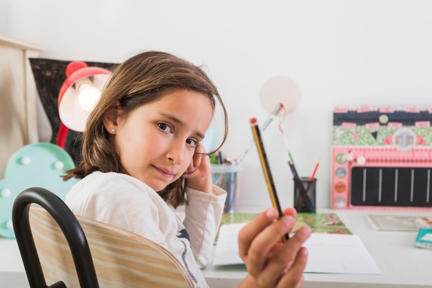 Mädchen, das Bleistift zur Kamera zeigt