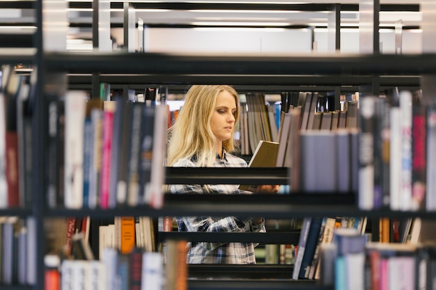 Mädchen, das bücher in der bibliothek nimmt