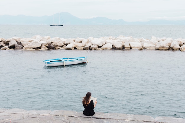 Kostenloses Foto mädchen, das ein buch am dock liest