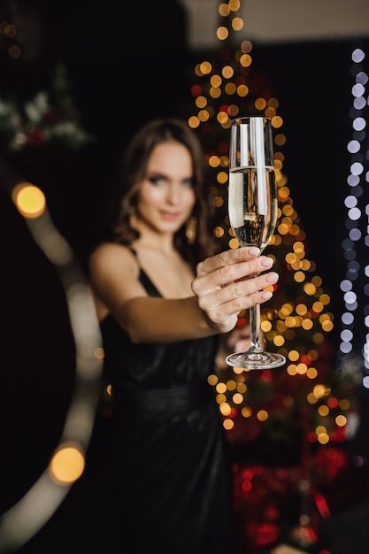 Mädchen, das ein Glas mit Champagner hält, steht im Vordergrund