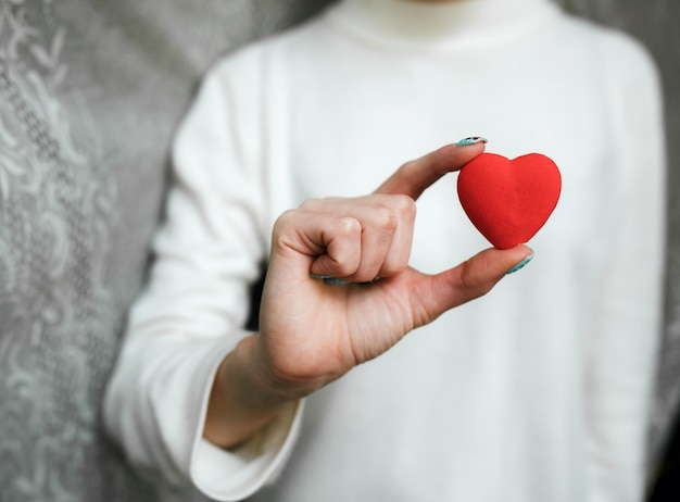 Mädchen, das ein kleines schönes Herz hält (kleine Dinge zum Valentinstag)