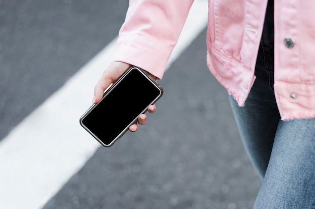 Kostenloses Foto mädchen, das ein smartphone in der hand hält