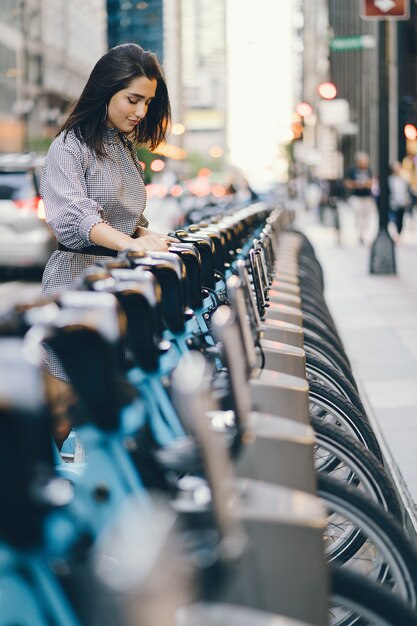 Mädchen, das ein Stadtfahrrad von einem Fahrradständer aus mietet