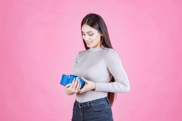 Mädchen, das eine blaue Geschenkbox hält und lächelt