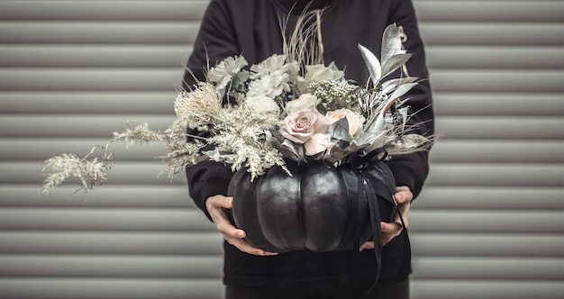 Kostenloses Foto mädchen, das eine blumenanordnung in einem kürbis hält.