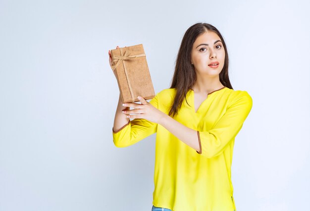 Mädchen, das eine Geschenkbox aus Karton hält und sich positiv fühlt.