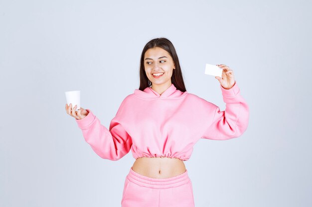 Mädchen, das eine Kaffeetasse in einer Hand hält und ihre Visitenkarte in einer anderen Hand präsentiert