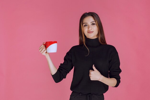 Mädchen, das eine Tasse Kaffee hat und den Geschmack genießt.