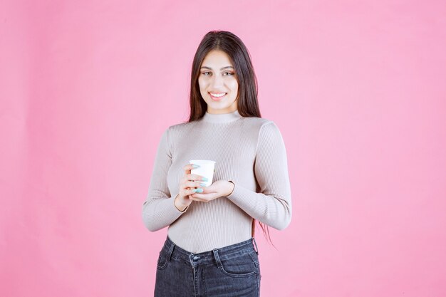 Mädchen, das eine weiße Einwegkaffeetasse hält, sie fördert oder den frischen Kaffee riecht