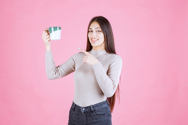 Mädchen, das eine weiße grüne Farbe Kaffeetasse hält und sich positiv fühlt