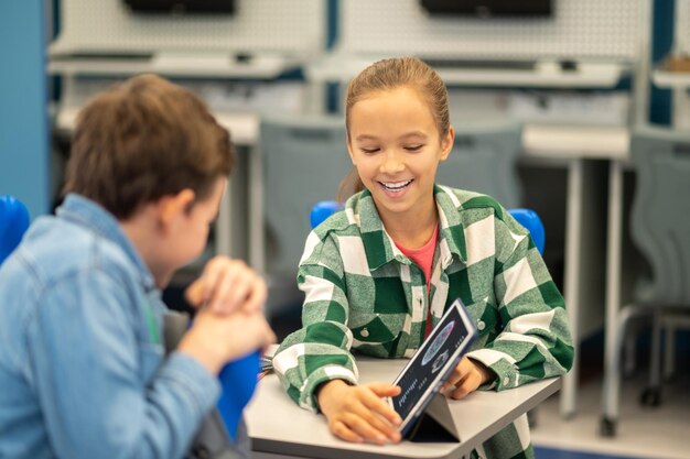 Mädchen, das einem interessierten Jungen den Tablet-Bildschirm zeigt