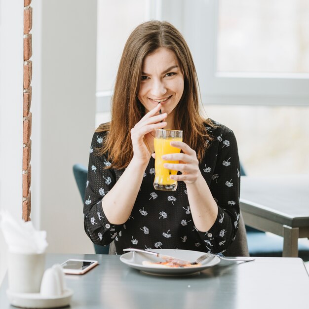 Mädchen, das einen Orangensaft in einem Restaurant isst