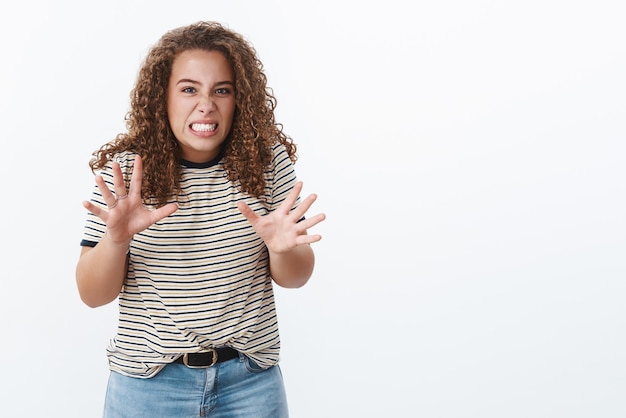 Mädchen, das ekelhafte, beunruhigende Geschichte nacherzählt, zuckend, Grimassen schneidendes Gesicht, widerwillige Abneigung, die Hände heben, Brust gestikulierend, Zähne zusammenbeißen, unzufrieden aussehen, intensive Abneigung, stehender weißer Hintergrund, emotional