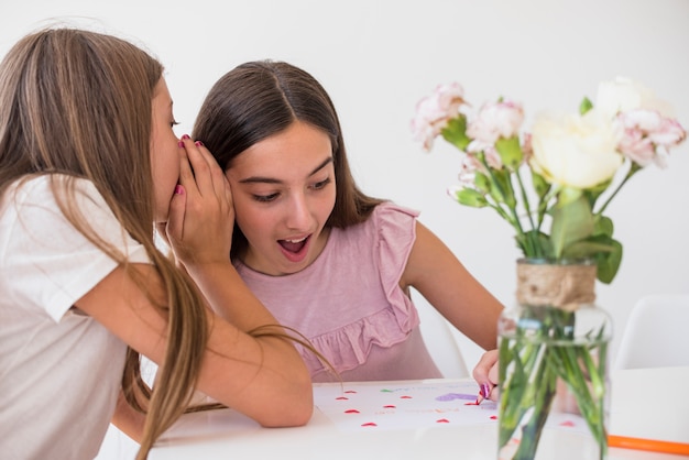 Kostenloses Foto mädchen, das etwas zur schwester flüstert