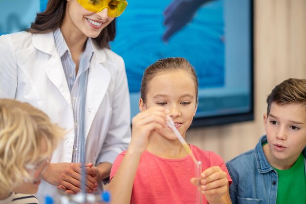 Mädchen, das Flüssigkeit von der Pipette zum Reagenzglas hinzufügt