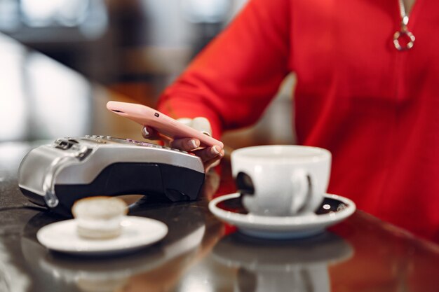 Mädchen, das für ihren Latte mit einem Smartphone durch kontaktlose PAY PASS-Technologie bezahlt