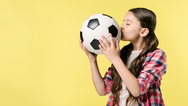 Kostenloses Foto mädchen, das fußball im studio küsst