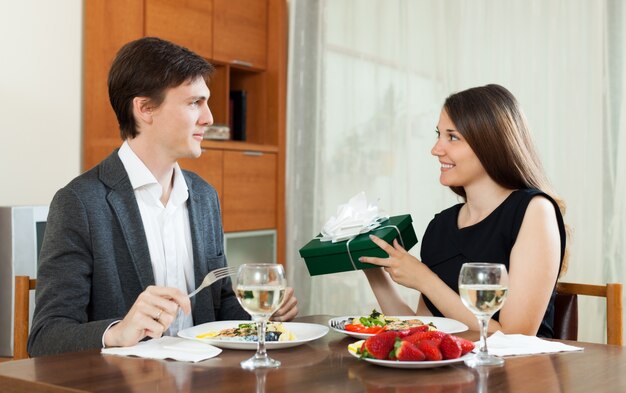 Mädchen, das Geschenk während des romantischen Abendessens gibt