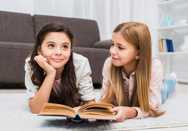 Mädchen, das ihren durchdachten Freund während Lesebuch im Wohnzimmer betrachtet
