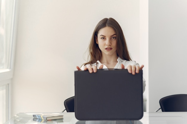 Mädchen, das im Büro mit einem Laptop sitzt