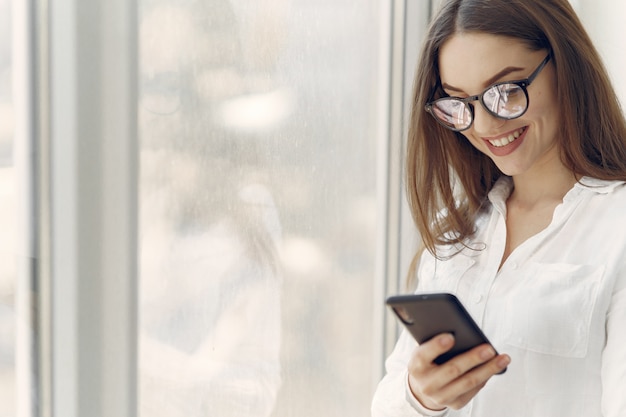 Mädchen, das im Büro mit einem Telefon steht