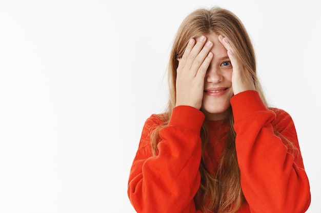 Mädchen, das in die Kamera späht, begierig darauf, Überraschung zu sehen, stirbt vor Vorfreude und Freude, schließt die Augen mit den Handflächen und reibt eine Hand ab