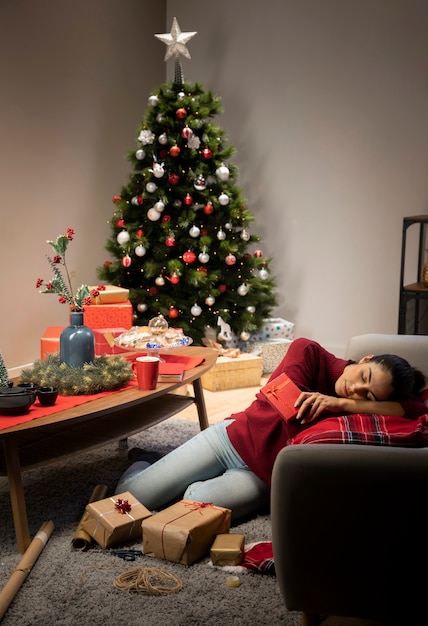 Mädchen, das in einem roten Pullover mit einem Weihnachtshintergrund sitzt