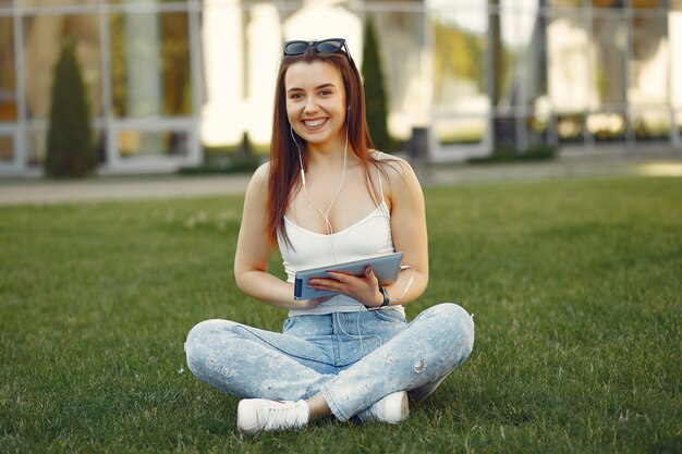 Mädchen, das in einem Universitätscampus unter Verwendung einer Tablette sitzt