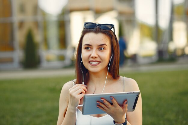 Mädchen, das in einem Universitätscampus unter Verwendung einer Tablette sitzt