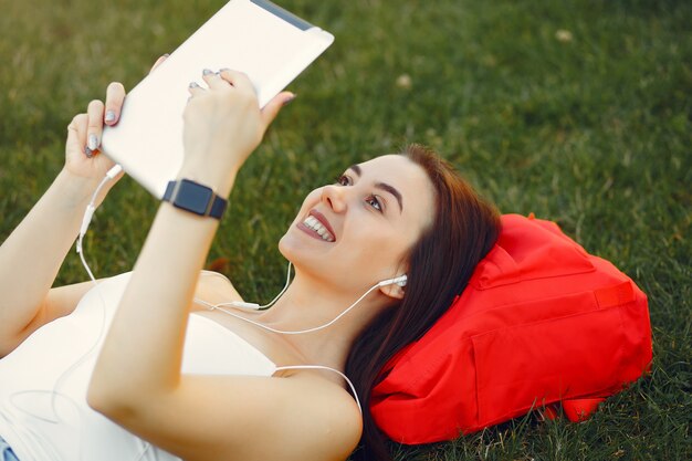 Mädchen, das in einem Universitätscampus unter Verwendung einer Tablette sitzt